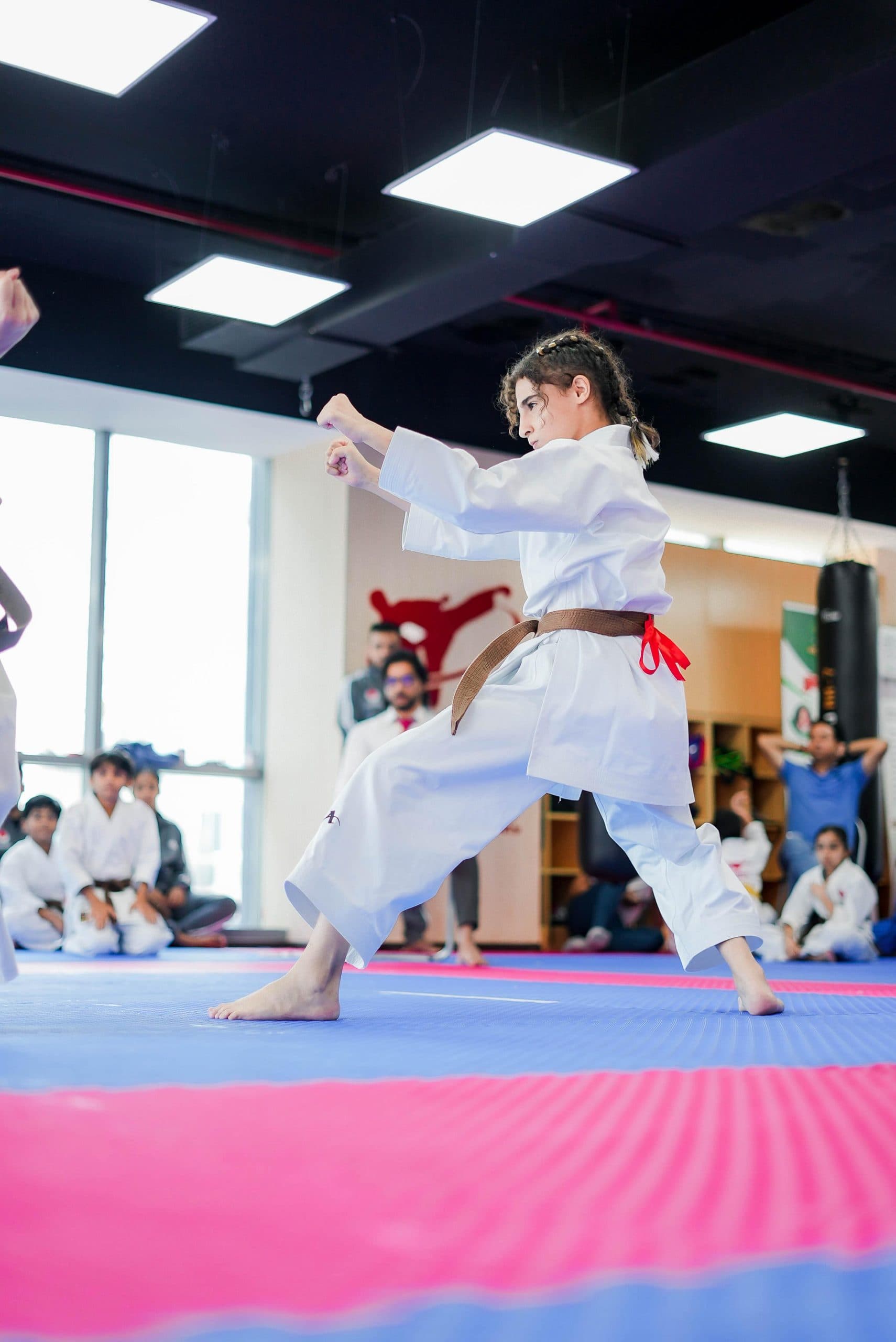 Young girl in brown belt performing a kata stance with a clenched fist raised