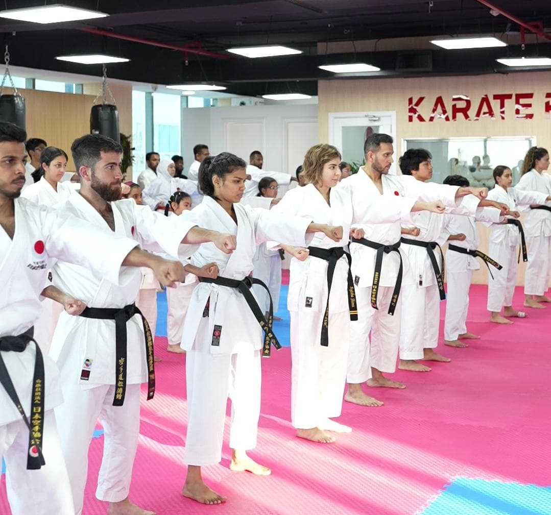 Rows of adult black belts punching in unison across the pink mats of the Karate Pro dojo