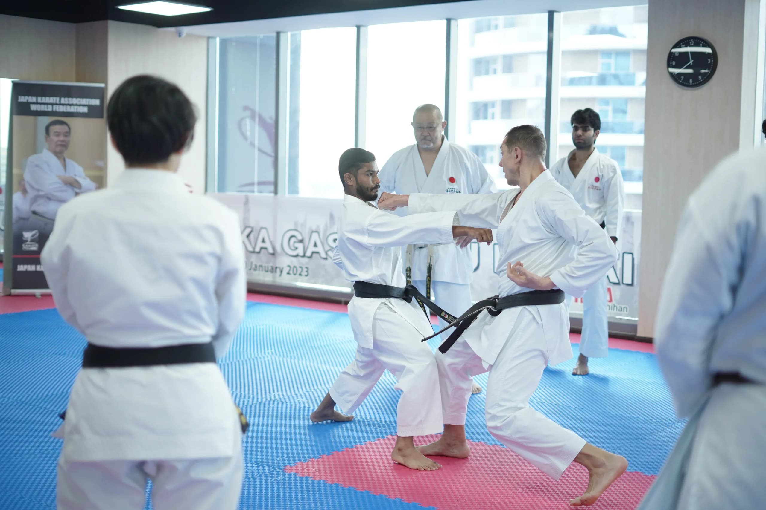 Instructor correcting a student's punch during a partner drill at a JKA training camp