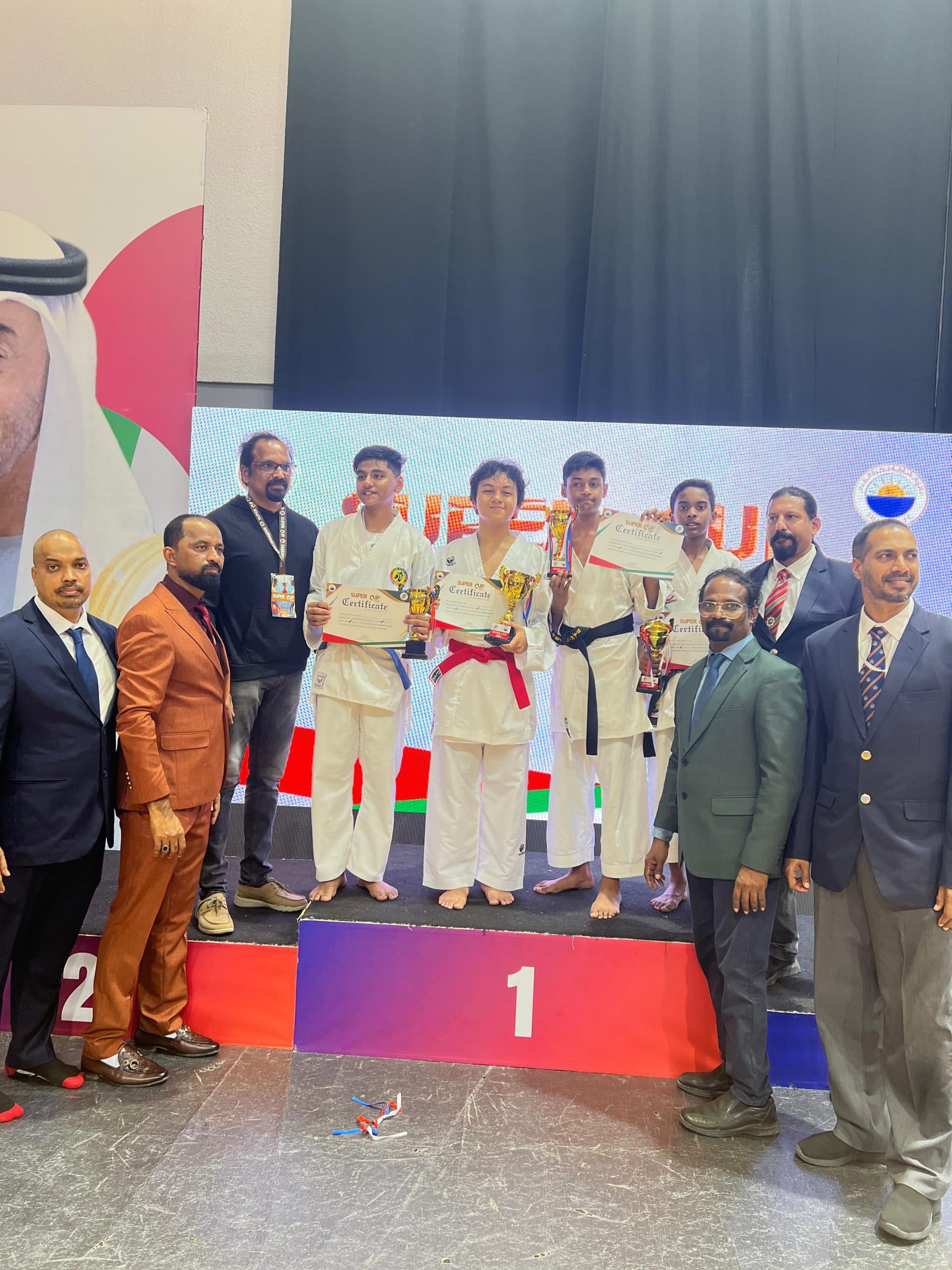Winners on a three-tier podium flanked by officials and coaches at a karate championship