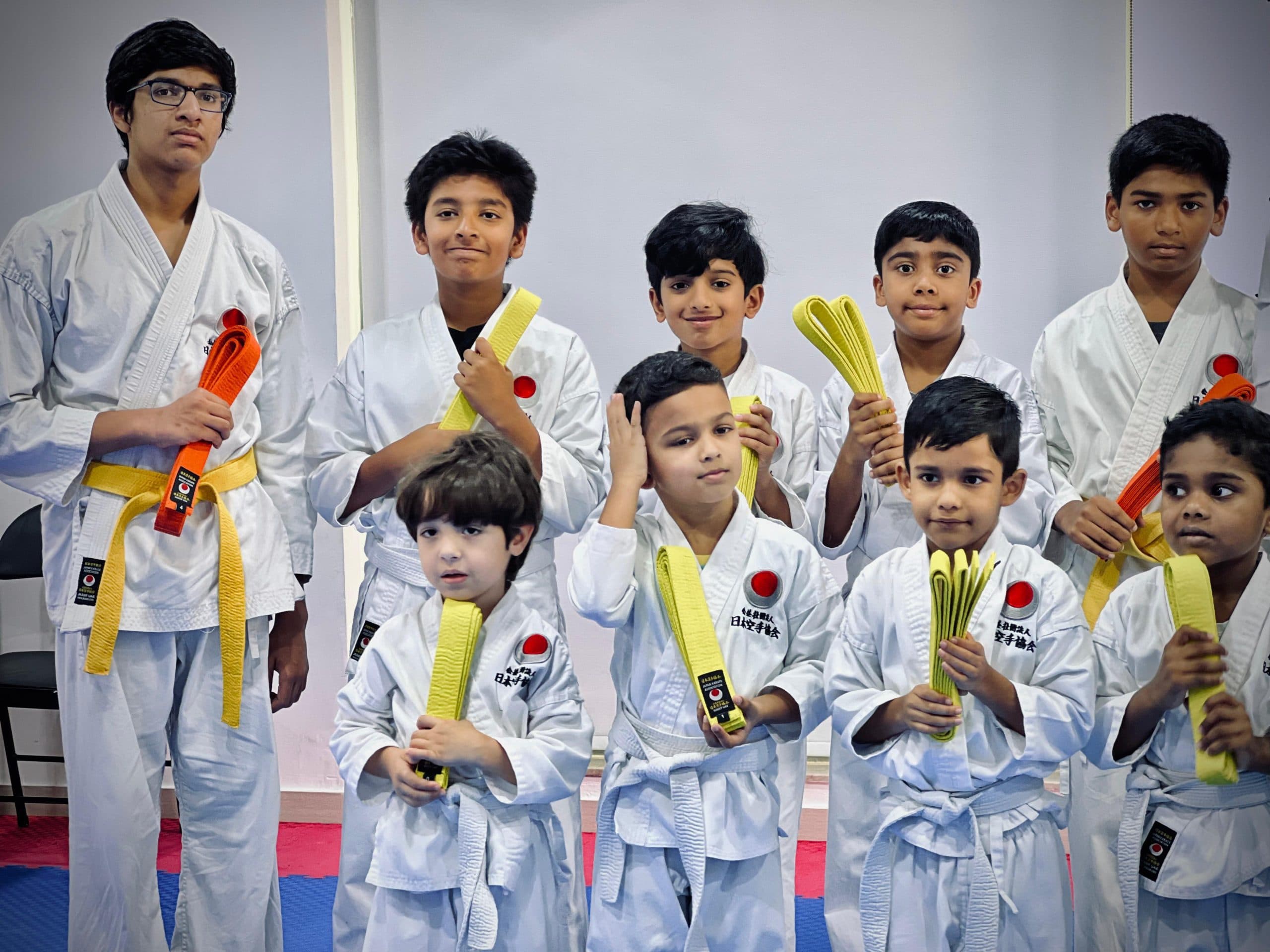 Group of young karate students proudly showing their newly awarded yellow and orange belts