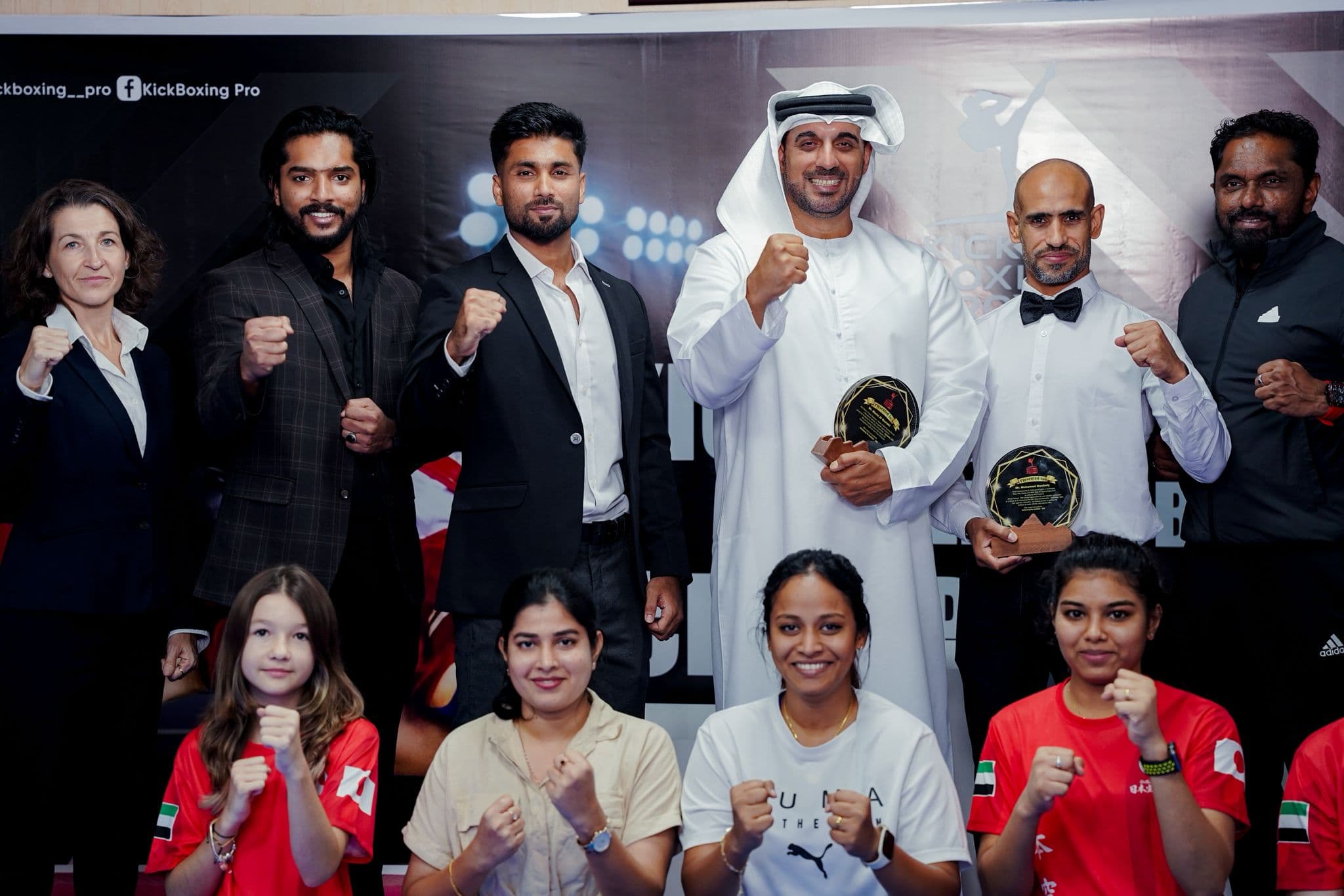 Officials, guests and young athletes posing with raised fists at the Kickboxing pro inter club championship 2025