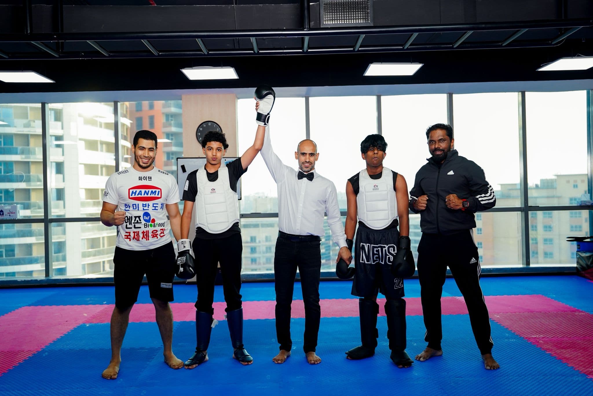 Referee raising the winner's arm between two kickboxers in body armour after a bout