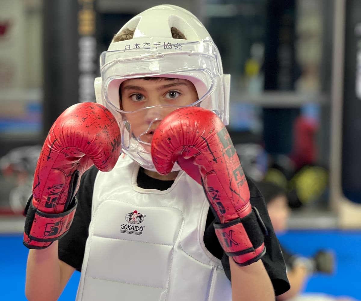 Young student in a clear face guard and red gloves ready to spar