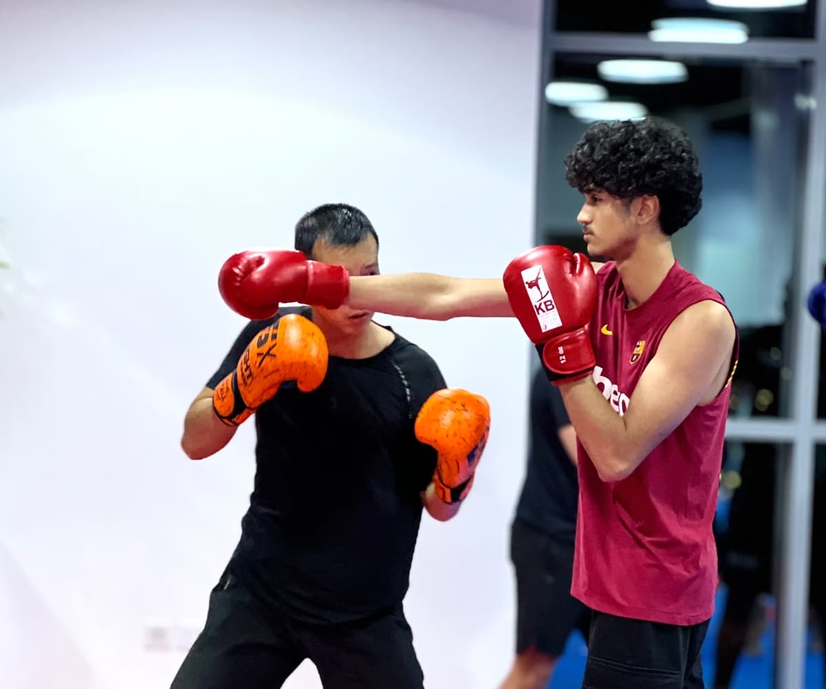 Two teenagers in gloves practising a straight punch against each other's guard