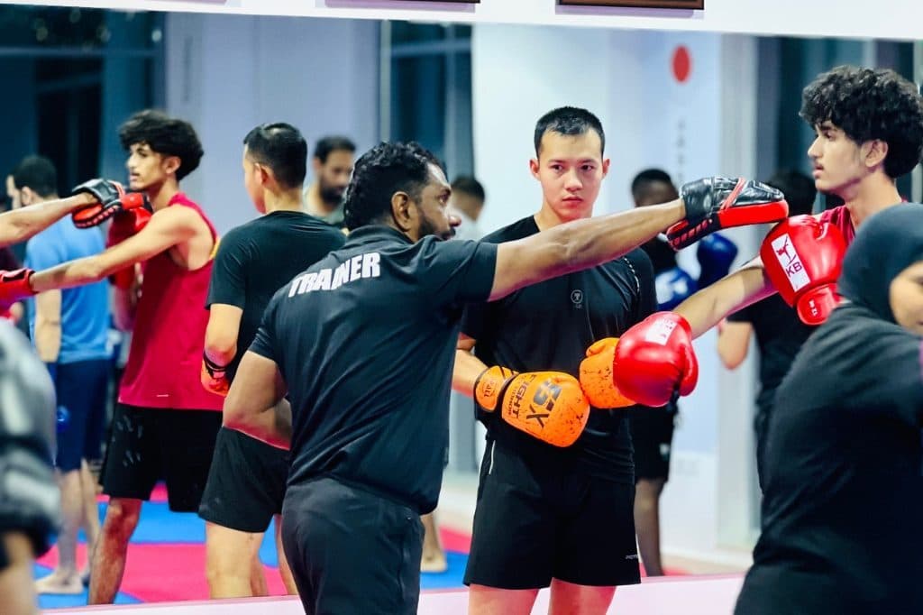Adults in gloves practising punches in pairs during an evening kickboxing class