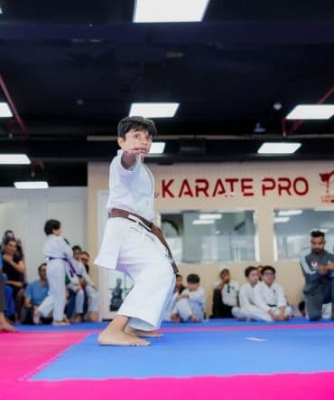 Young boy in brown belt performing kata while classmates watch from the mats