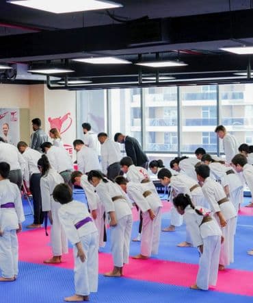 Rows of young students bowing together at the start of a kids karate class