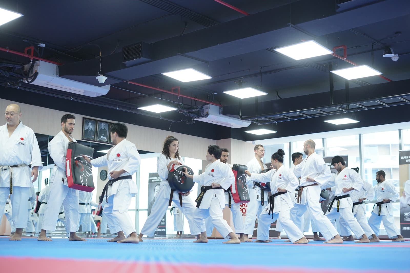 Students striking hand-held pads in a line during a karate class in the dojo