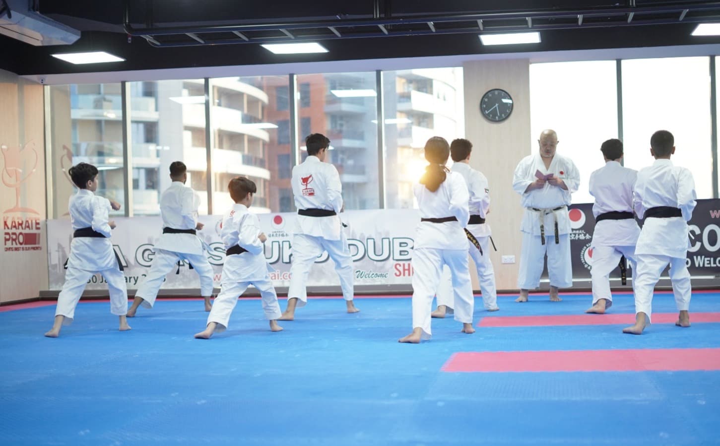 Students practising kata in rows at a JKA Gasshuku Dubai seminar by the dojo windows