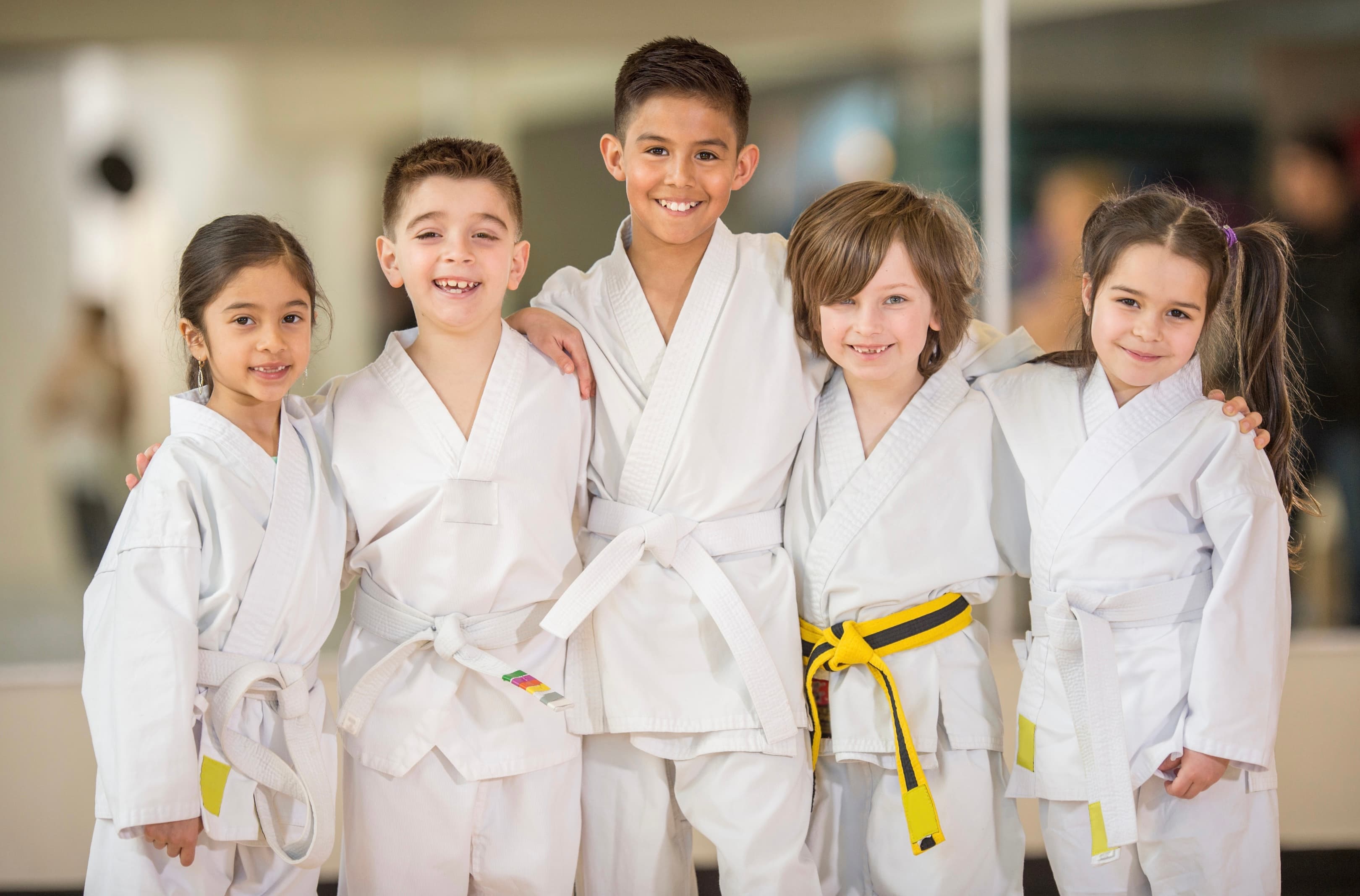 Kids karate class at the Dubai Silicon Oasis branch posing in white gi with their coloured belts