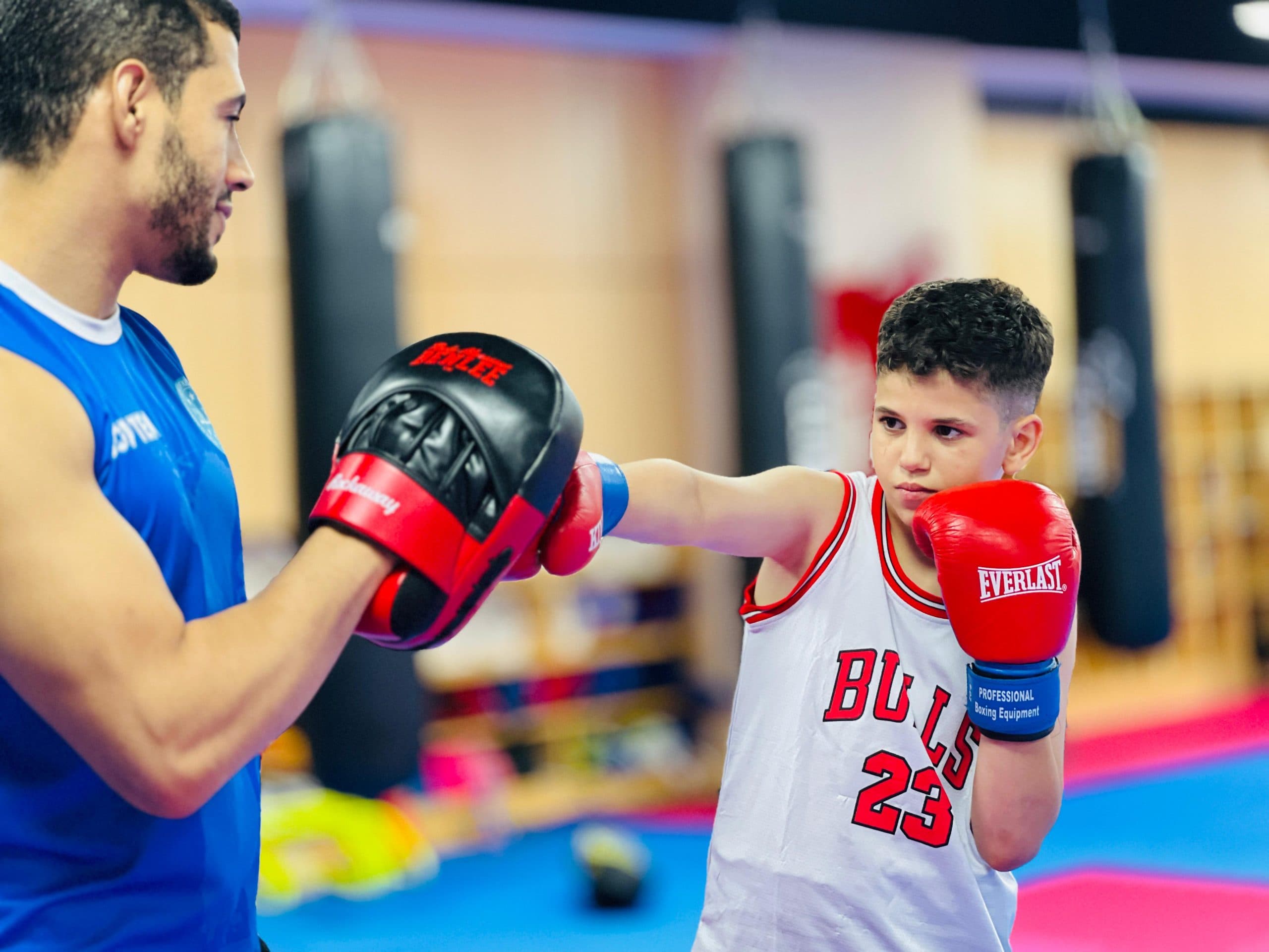 Coach running a pad drill with a young student in blue gloves