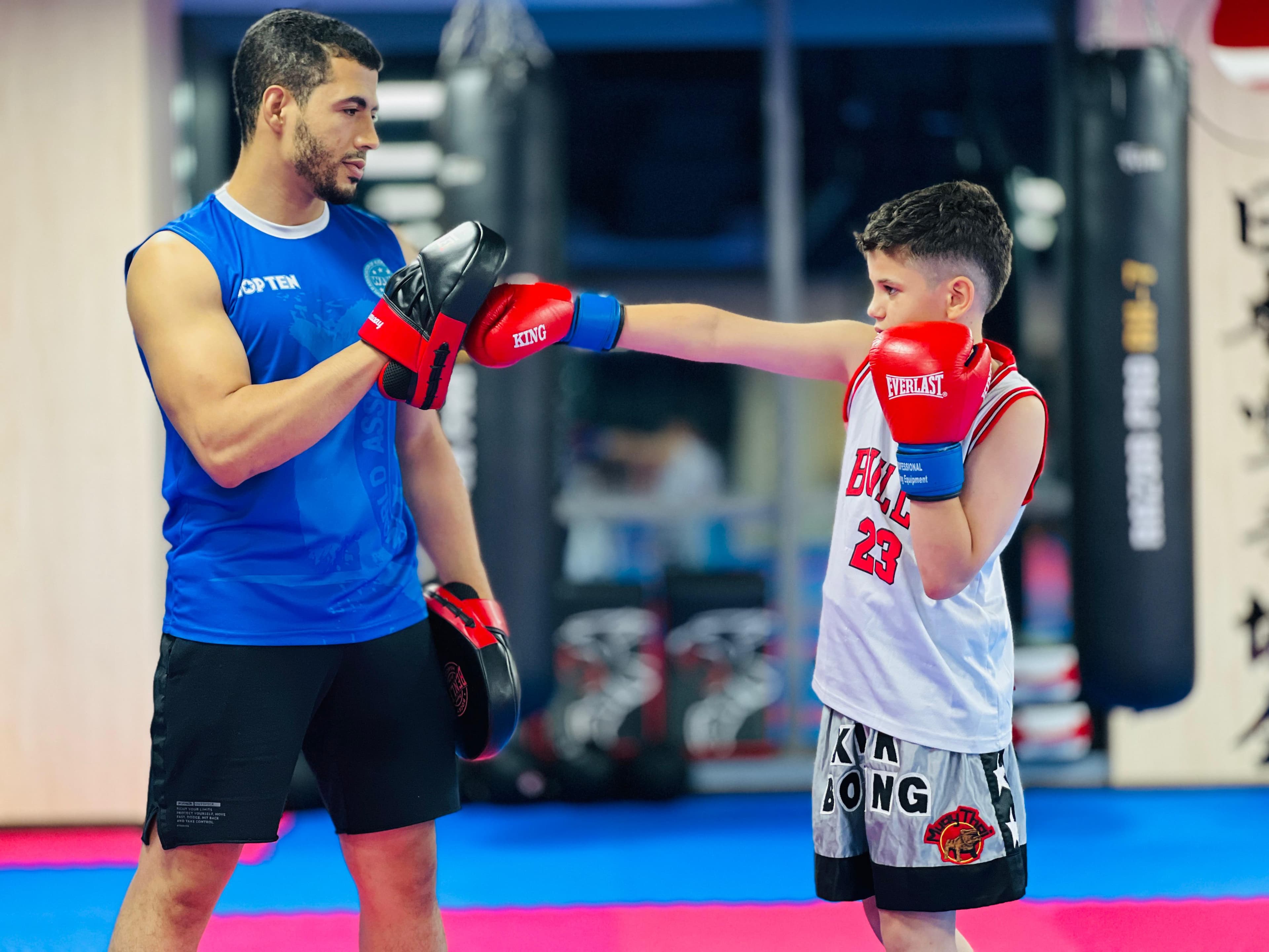 Coach holding pads for a student wearing red gloves during a striking drill