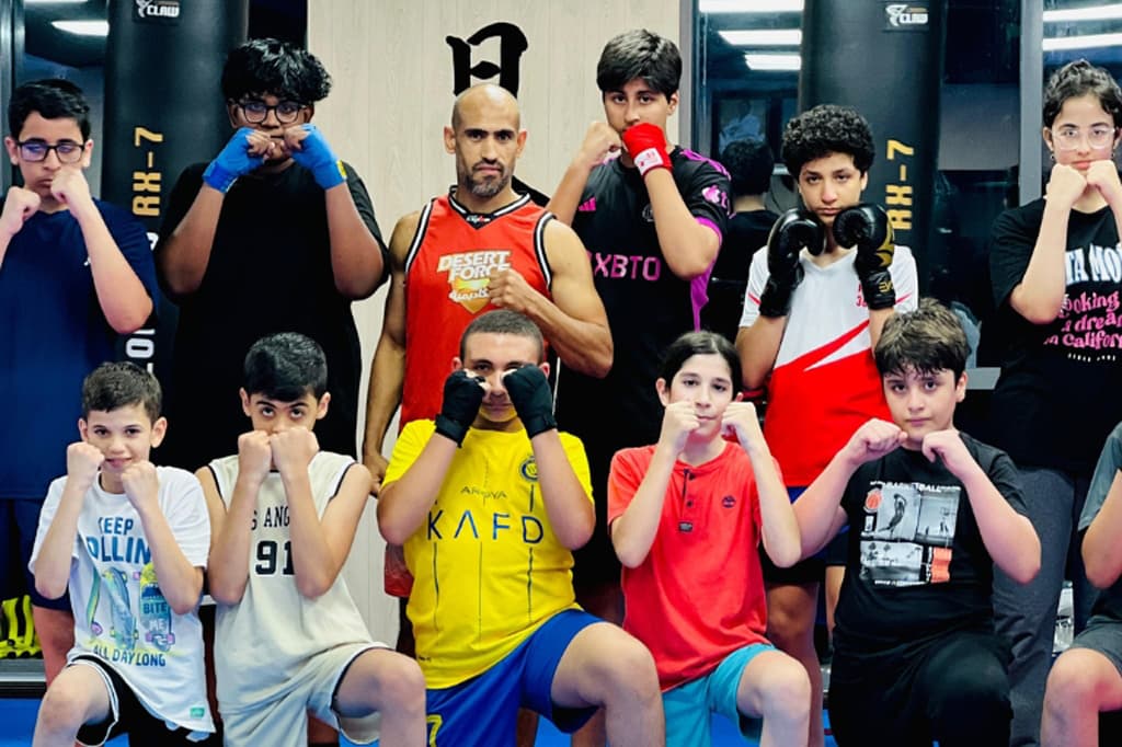Kids kickboxing class posing together in matching black t-shirts