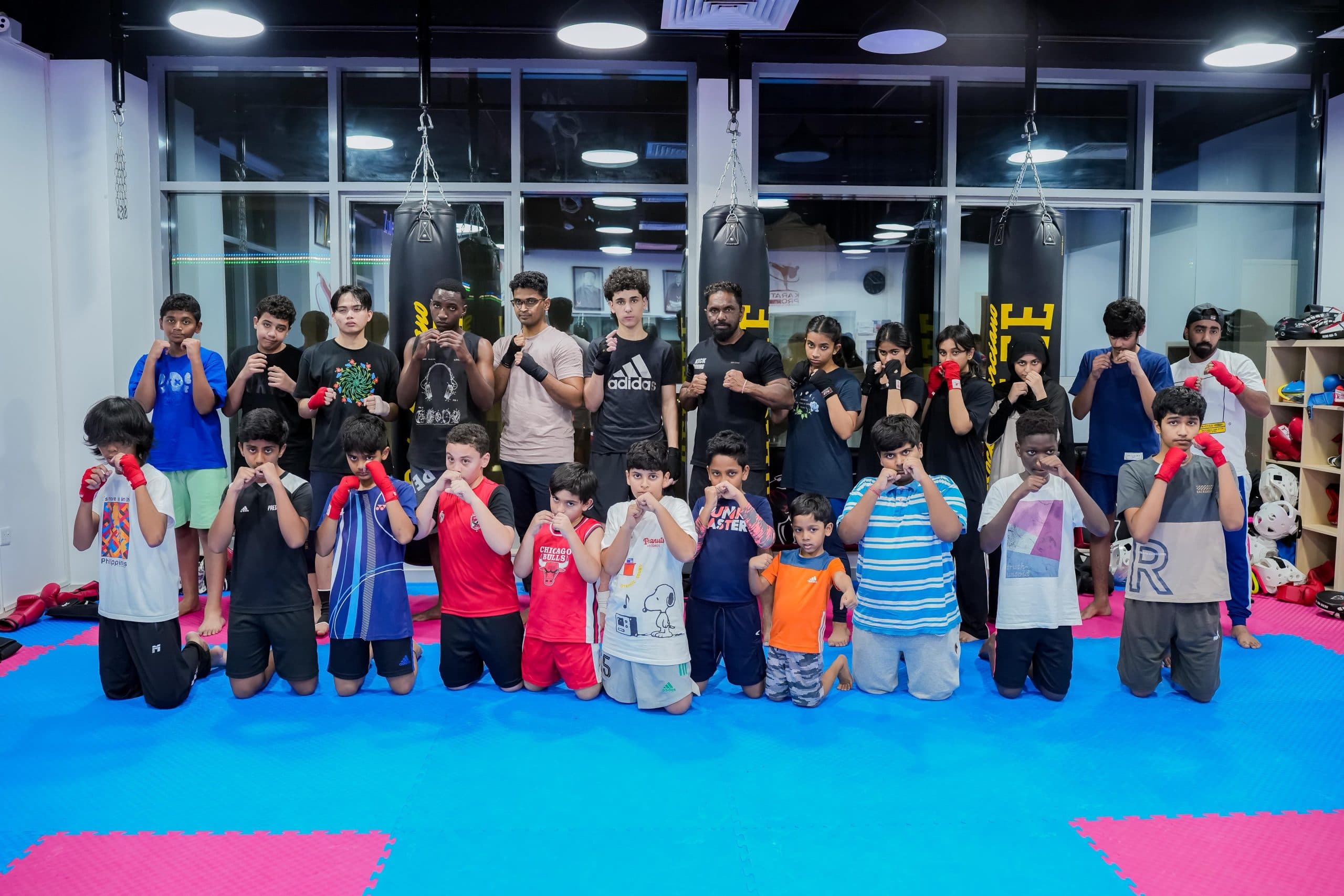 A kids kickboxing class posing together in gloves after training