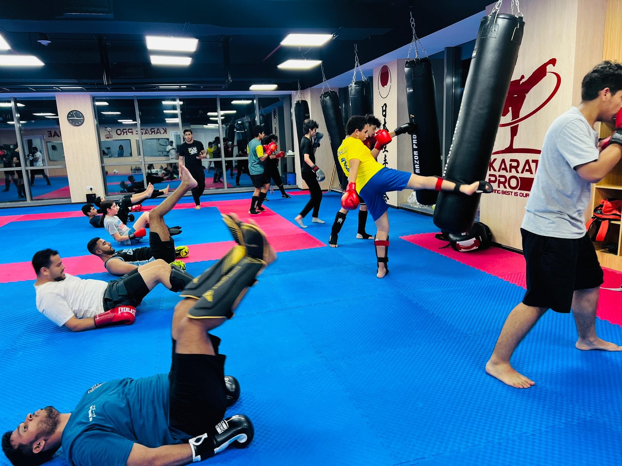 Adults training kicks on pads and bags in a busy kickboxing class
