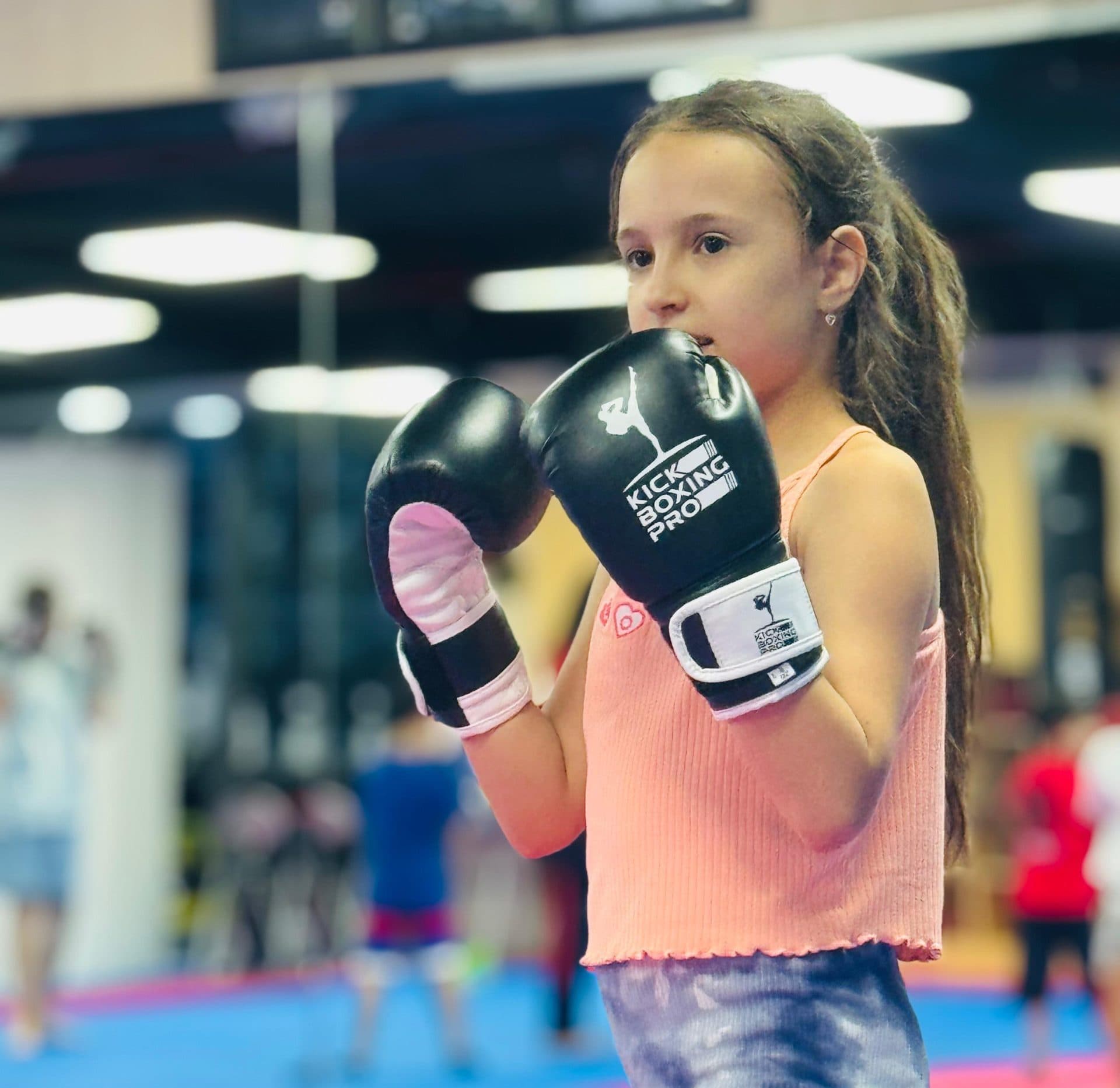 Young girl in boxing gloves ready for kickboxing class