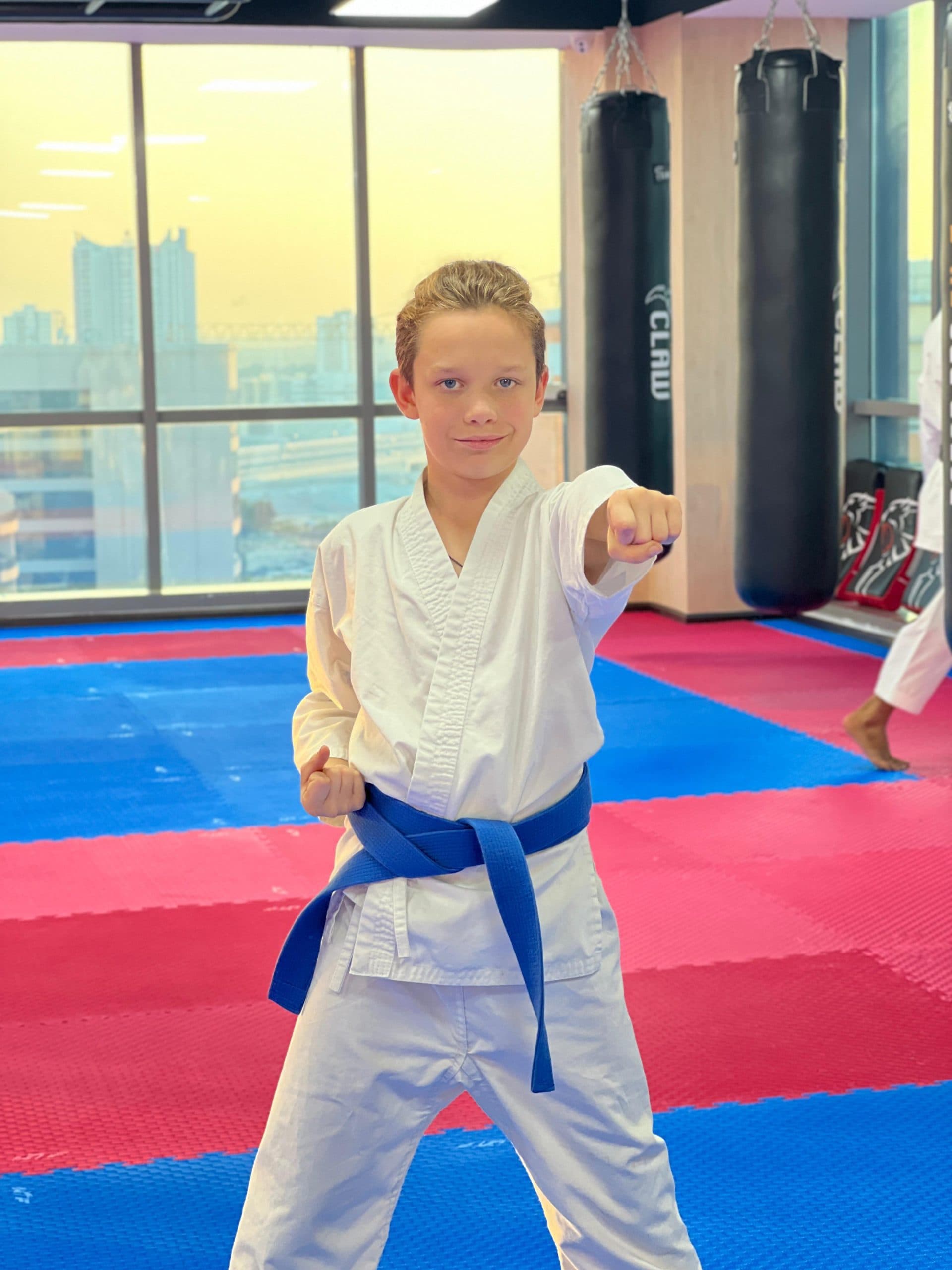 Boy in blue belt practising a punch during summer camp